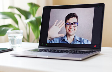 Young man talking by video call on a computer monitor - Employee's report at an online briefing on business success - Online homeschooling amid the coronavirus epidemic