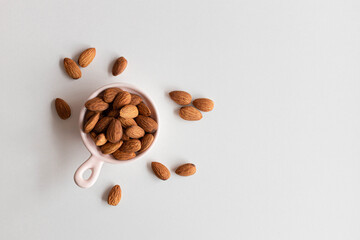 Fresh almonds nuts in pink plate on a white background. Flat lay, top view, copy space.