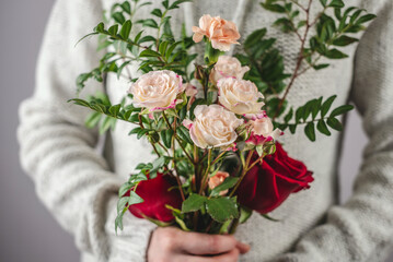 A woman in a sweater is holding a tenderness bouquet of flowers. Concept of springtime and a pleasant romantic mood. Closeup