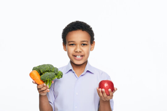 African American boy holding vegetables and fruits in his hands. Healthy vegetarian food concept for kids