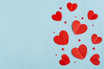Valentine's Day background February 14th. Confetti, red hearts of paper on pastel blue background. Valentines day concept. Flat lay, top view, copy space.