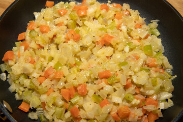 A selection of mixed cooking ingredients frying in a pan including carrots, spring onions and celery.