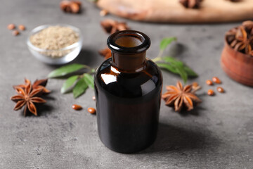 Bottle of essential oil and anise on grey table