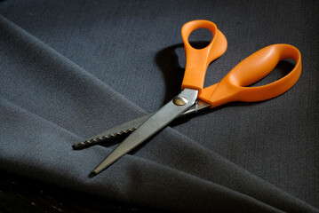 Obraz premium Tailor's scissors lie on the surface of a piece of woolen fabric, close-up, top view. Tailoring.