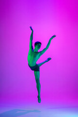 Fototapeta na wymiar Emotions. Young and graceful ballet dancer on purple studio background in neon light. Art, motion, action, flexibility, inspiration concept. Flexible caucasian ballet dancer, moves in glow.