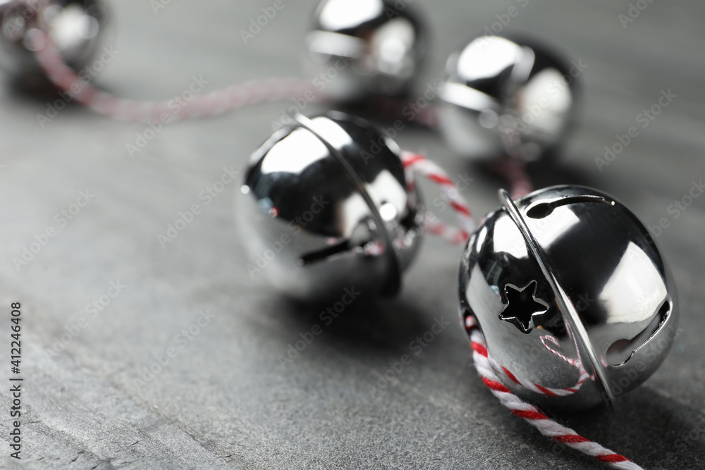 Wall mural Shiny silver sleigh bells on grey stone table, closeup. Space for text