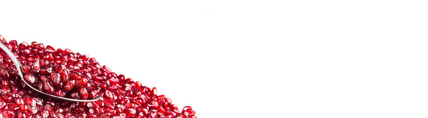 Pomegranate berries on a spoon. Pomegranate seeds on a white background.