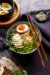 Bowl of asian ramen soup with noodles, spring onion, sliced egg and mushrooms on black table. Japanese dish in black.
- 412247433
