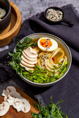 Bowl of asian ramen soup with noodles, spring onion, sliced egg and mushrooms on black table. Japanese dish in black.
- 412248226