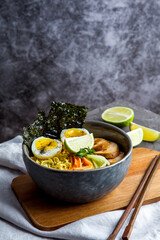 Bowl of asian ramen soup with noodles, spring onion, sliced egg and mushrooms on black table. Japanese dish in black.
- 412248299