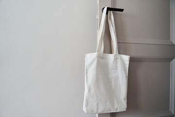 Eco friendly concept with white canvas tote bag hanging on door knob with two toned colored, Eco...
