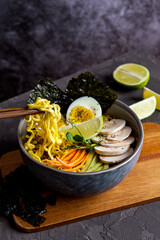 Bowl of asian ramen soup with noodles, spring onion, sliced egg and mushrooms on black table. Japanese dish in black.
- 412248696