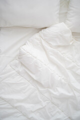 Soft white pillows on messy bed, closeup.