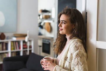 young woman drinking morning coffee in her apartment