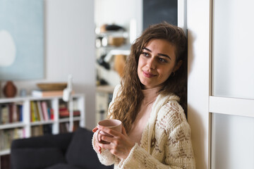 young woman drinking morning coffee in her apartment