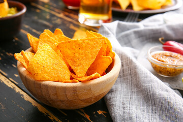 Bowl with tasty nachos on dark wooden background, closeup