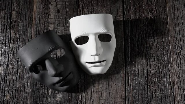 Black and white masks on a wooden vintage background, symbol of anonymity and theater. With shadows close-up, copy space