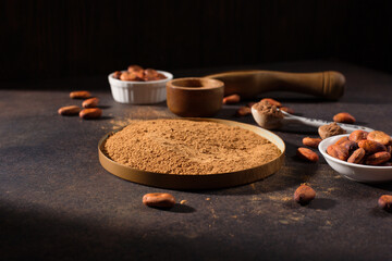Organic cocoa powder and aromatic raw cocoa beans on dark rustic wooden background.