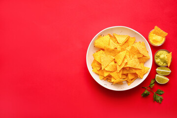 Plate with tasty nachos and sauces on color background