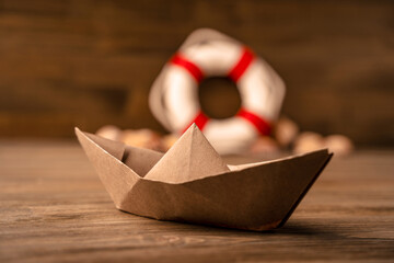 Summer sea banner. Lifebuoy, seashells and a paper boat on a wooden background