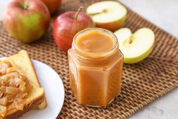 Jar and toast with sweet apple jam on light background