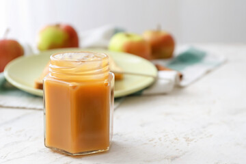 Jar of sweet apple jam on light background