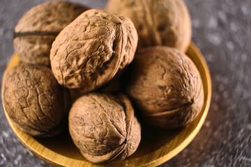 Walnut in wooden bowl on black background with copy space