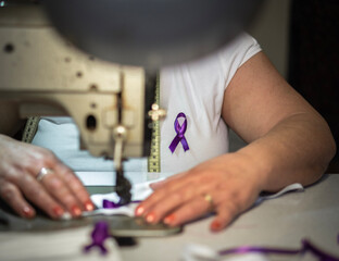 Working woman, woman sewing purple ribbon on face masks. women's Day. Gender violence