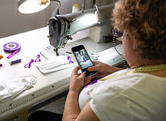 Working woman, woman taking photo of a purple ribbon sewn on masks. women's Day. Gender violence