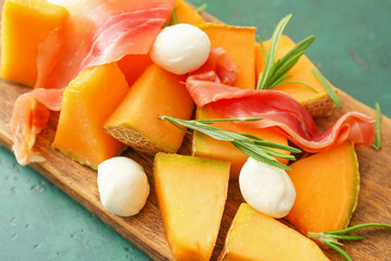 Board with delicious melon, mozzarella and prosciutto on color background