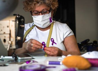 Working woman, woman sewing purple ribbon on face masks. women's Day. Gender violence