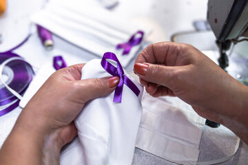 Working woman, woman sewing purple ribbon on face masks. women's Day. Gender violence