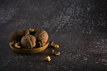 Walnut in wooden bowl on black background with copy space