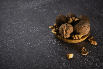 Walnut in wooden bowl on black background with copy space