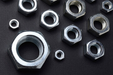 new chrome nuts of different sizes are laid out against a dark background. close-up.