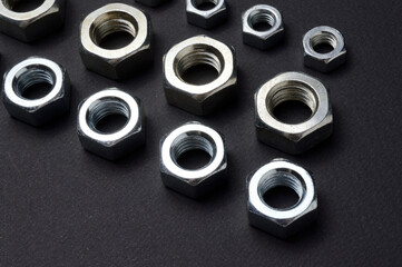 new chrome nuts of different sizes are laid out against a dark background. close-up.