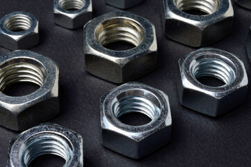 new chrome nuts of different sizes are laid out against a dark background. close-up.