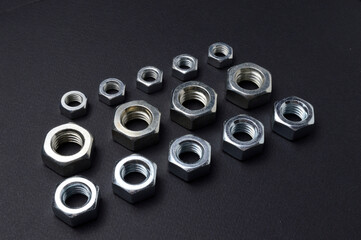 new chrome nuts of different sizes are laid out against a dark background. close-up.