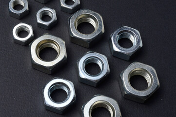 new chrome nuts of different sizes are laid out against a dark background. close-up.