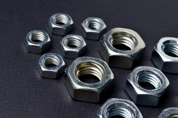 new chrome nuts of different sizes are laid out against a dark background. close-up.