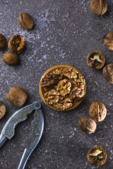 Vintage walnut cracker and walnuts on a dark texture background.