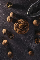 Vintage walnut cracker and walnuts on a dark texture background.