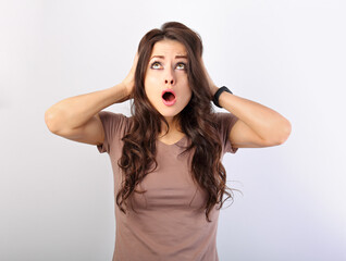 Angry young surprising business woman holding the head the hands with big eyes looking up. Fun...