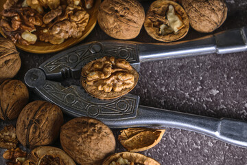 Vintage walnut cracker and walnuts on a dark texture background.