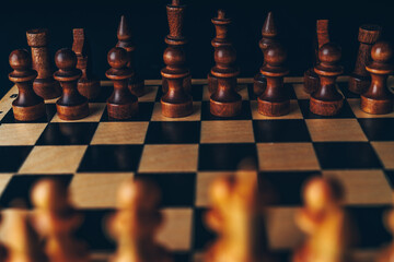 White and black wooden pieces on a chessboard. A chessboard set up during a game on a black background