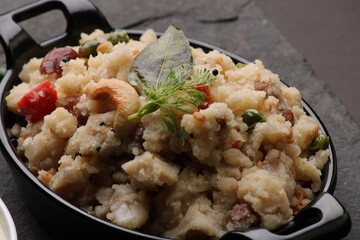 Rice upma, a south Indian vegetarian breakfast made from shredded rice and vegetables like carrot andpeas, with coconut chutney as a side dish.