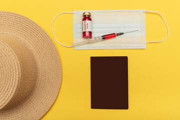 Traveling by plane in a pandemic. On a yellow background hat, passport, mask.