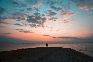 Fototapeta na wymiar Silhouette of a happy loving couple at sunset on the seashore
