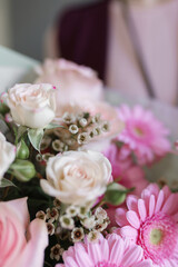 image of a girl in apron holding a flower in her hands with a manicure on a grey background	