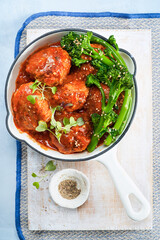 Tikka Masala Meatballs with broccolini, broccoli florets green vegetable baby broccoli, in cast iron pan, vegan healthy dinner, lunch on light blue background. Close-up. Top view, indian food recipe.